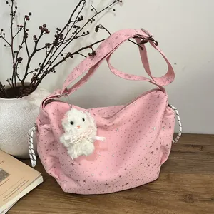 Pink canvas tote bag with silver star prints and a white plush bunny charm on a table