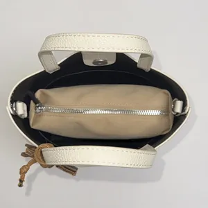 White lychee leather bucket bag with canvas inner pouch and brown tassel charm top view