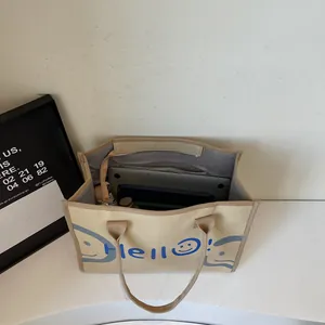 Minimalist beige canvas tote bag with blue Hello text and interior items layout