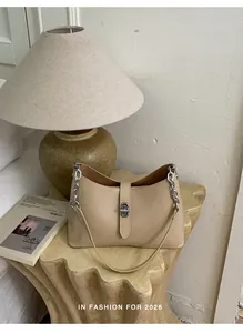Detail view of beige leather hobo bag with silver chain on a wooden table setup
