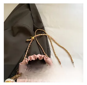 Detail of pink dumpling bag featuring woven chain strap and pleated leather handle texture