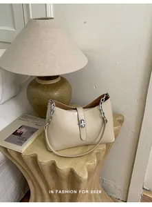 Detail of minimalist beige underarm bag featuring silver twist lock and leather chain strap