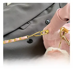 Close-up of pink textured bag featuring golden metal clasp and plush cat pendant charm