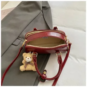 Sac boston chic en cuir rouge foncé avec pendentif ours et bandoulière amovible