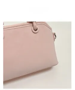 Close-up of smooth pink leather texture and metal eyelet detail on a chic handbag