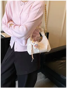 Detail of off-white dumpling bag with textured fabric, gold chain and plush charm