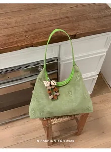 Dettaglio borsa a spalla in camoscio verde chiaro con fiori di strass e ciondolo