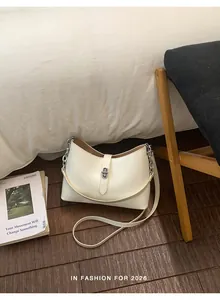 Detail of the elegant cream white leather bucket bag featuring a silver metal twist lock