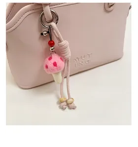 Detail of pink felt mushroom charm with red dots on a stylish leather handbag handle