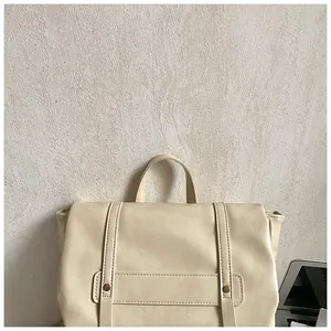 Dettaglio dello zaino in pelle bianco crema con cinturini con borchie dorate e patta