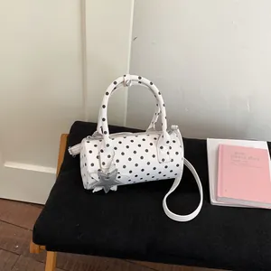 Detailed view of polka dot barrel handbag with star charm on a black bench