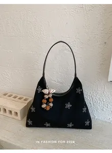 Dettaglio della borsa hobo nera con motivi floreali in strass e ciondoli di peluche