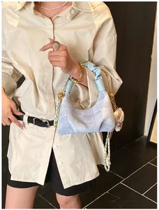 Detail of light blue textured handbag with cloud-shaped pleated handle and gold chain strap