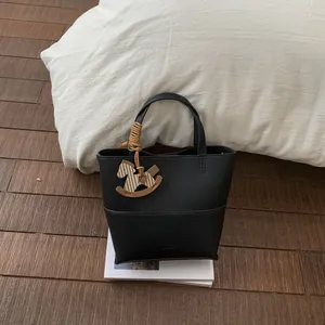 Detail of black pebbled leather bucket bag featuring a unique horse-shaped charm pendant