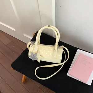 Close-up of yellow polka dot boston bag with star charm and detachable shoulder strap