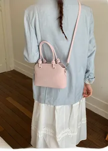 Detail of pink leather handbag with MUTING embossing and unique knotted handle design