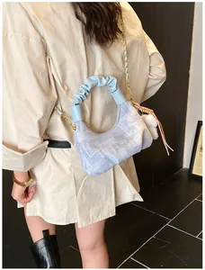 Detail of light blue dumpling bag with ruched handle and metallic chain strap