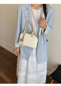 Detail of cream white PU handbag with embossed letters and knot handle design