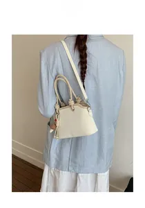 Detail of cream white leather bag featuring a unique knotted handle and mushroom charm