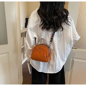 Detalle de bolso bandolera de nailon naranja con correa LOVE arcoíris y doble cremallera