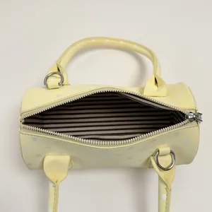 Top view of yellow polka dot cylinder handbag showing striped lining and zipper closure
