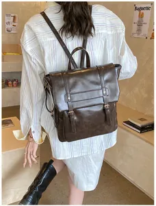 Dettaglio di zaino in pelle marrone scuro con fibbie in metallo in un ambiente café retrò