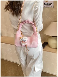 Detail of pink plaid handbag featuring a pleated leather handle and a cute plush cat charm