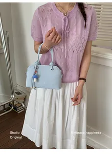 Detail of light blue faux leather handbag with MUT ING lettering and mushroom charm