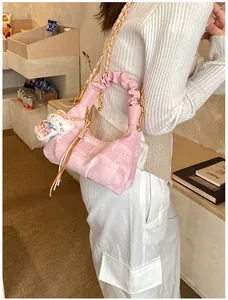 Pink dumpling bag with gold chain and plush kitten charm shown in lifestyle setting