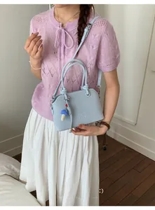 Close-up of light blue leather handbag with MUTING logo and mushroom charm detail