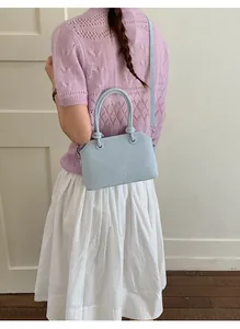 Detail of light blue matte leather handbag with embossed letters and round handle