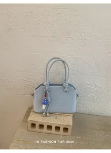 Detailed close-up of light blue faux suede handbag with a cute mushroom pendant