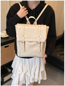 Dettaglio di uno zaino vintage in pelle crema indossato da una modella in un interno