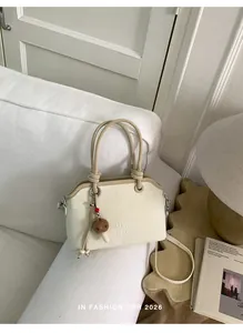 Detail view of cream leather handbag with mushroom charm and contrast handle on a sofa