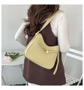 Detail of cream yellow hobo shoulder bag with metal buckle and long tassel fringes