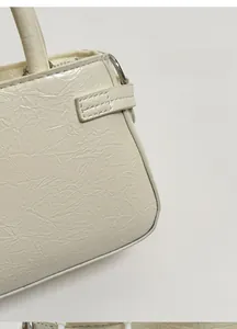 Close-up of cream-white handbag showing soft crinkled leather texture and silver hardware
