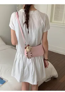 Detail of pink faux leather shoulder bag with a cute bear charm and beaded strap