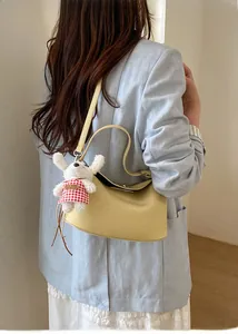 Detail of light yellow lychee grain leather handbag featuring a plush puppy charm