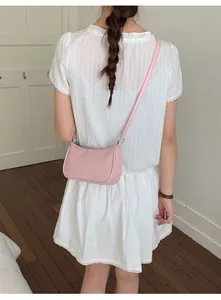 Rear view of a model wearing the light pink leather mini crossbody bag in a home setting