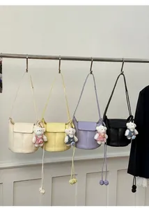 Detail view of colorful PU leather bucket bags with stitching and cute bear charms