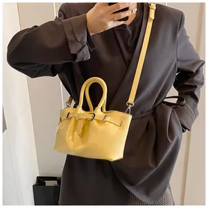 Detailed view of bright yellow bucket bag with belt buckle decor and silver metal hardware