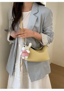 Pale yellow pebbled leather handbag with cute plush charm on a blue suit model