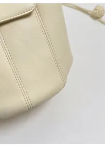 Macro shot of off-white leather texture with double stitching on the bucket bag detail