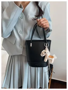 Detail of black lychee grain bucket bag with beige horse charm and embossed logo