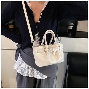Detail shot of a creamy white glossy bucket bag featuring a decorative metal belt buckle strap