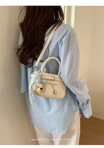 Close-up of a white leather handbag with light blue bow and bear charm detail