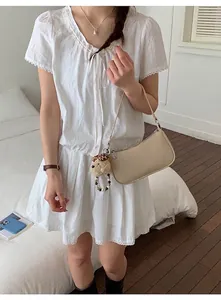 Detail of cream leather shoulder bag featuring a plush dog charm and beaded strap