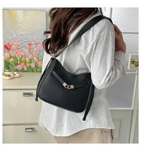 Detail of a minimalist black crescent hobo bag with a light gold metallic buckle clasp