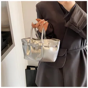 Close-up of metallic silver bucket bag featuring a polished belt buckle and double handles