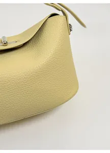 Detailed macro view of creamy leather texture and golden metal buckle on crossbody bag